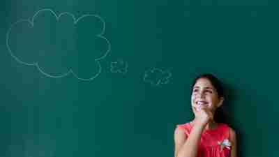 student with ADHD thinking about goals by chalkboard in a classroom