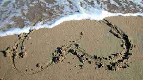 Heart in sand being washed away by waves, representing relationship issues of ADHD people