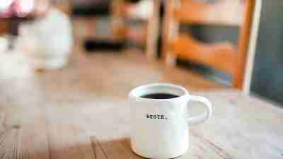 white coffee mug on table with the word "Begin" on it