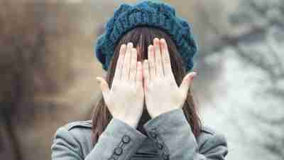 Girl with ADHD covers face with hands outside