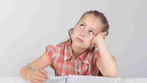 Young girl looks bored, distracted as she sits with her binder doing homework.