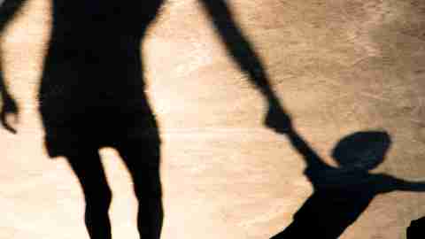 Shadows silhouettes of mother and son pulling her hand on summer promenade in sepia black and white