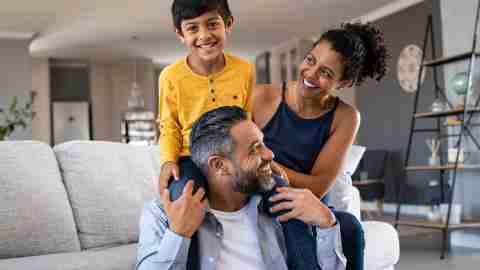 Family sitting in living room, dad carrying child over shoulders