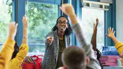 Teacher in classroom points to student raising hand