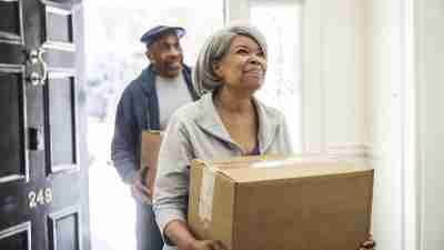 Senior couple carrying moving boxes into new house, thinking about how to organize for their new phase of life.