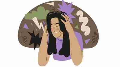 A woman with black hair holds her head in her hands as she experiences rejection sensitive dysphoria. RSD, an ADHD trait, may be an evolutionary adaptation to fear of rejection.