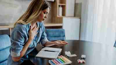 A young woman is taking medication from her pill organizer.