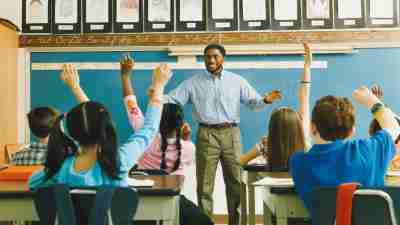Teacher Standing in Front of a Class of Raised Hands