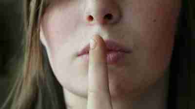 Women with ADHD with her finger held to her lips, representing the need for an inclusive culture at work