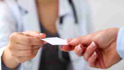Close up of doctor handing business card to patient. IPV screening, safety cards save lives.