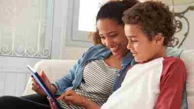 Mother And ADHD Son Sitting On Sofa Using Digital Tablet