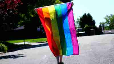 Gender nonconforming person holding rainbow flag for Pride Month