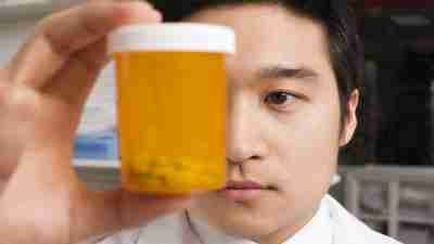 Adderall dosage: Doctor holding pill bottle up to face with ADHD medication inside it
