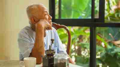A senior man with ADHD, staring quietly out the window of his home